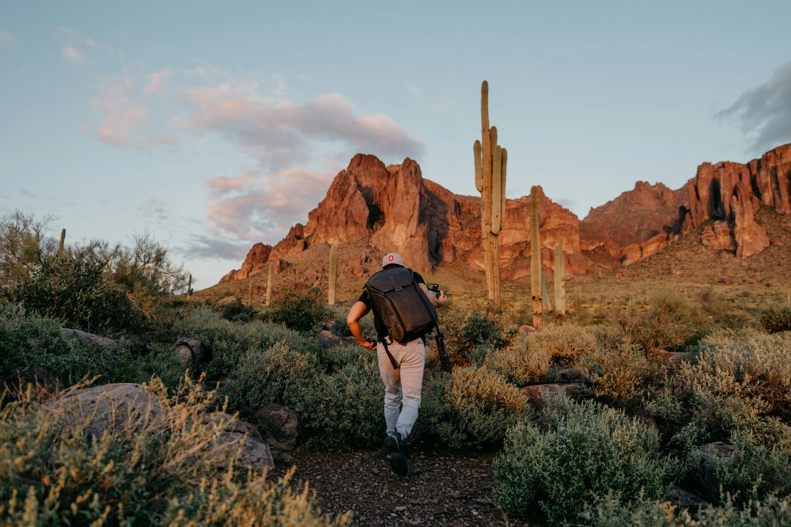 Hiker on a desert trail toward the Superstition Mountains near Mesa, Arizona, at golden hour
